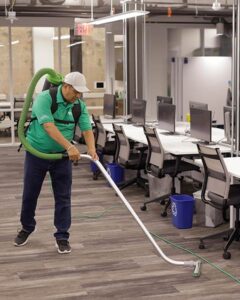 An ABS Cleaners employee vacuums an office conference room